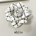 Macro detail of white houndstooth camellia brooch in vintage tweed fabric texture - White Black Plaid
