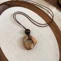 Makro-Detail des unregelmäßigen Harz-Holz-Anhängers mit braunen Perlen an Ethno-Kette - Faux Achat Textur Unregelmäßiger Stil (Kaffee)