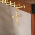 Dettaglio di un ciondolo a croce dorata con zirconi su un supporto per gioielli in legno - Stile Croce 12