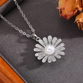 Gros plan du pendentif marguerite avec perle et cristaux sur un plateau texturé gris - Collier Marguerite Argentée avec Perle (T024)