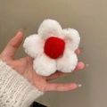 Detail of plush daisy hair claw featuring soft white petals and a red center - White