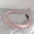 Detailed macro view of pink satin padded headband with handmade label on soft background - Pink