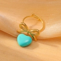 Elegant gold bow ring with light blue heart pendant on a sparkling background - Cyan Blue Style