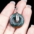 Hand holding a green Aventurine donut pendant with a silver metallic bail clasp - 20mm Indian Agate