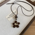 Gros plan du pendentif fleur léopard floqué avec diamant carré et cordon marron - Style Fleur Léopard Corde Marron Foncé