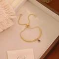 Dettaglio del bracciale dorato regolabile con lettera F in cristallo e malocchio - Lettera F