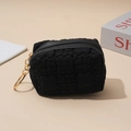 Monedero negro con textura de gofre, llavero dorado y cremallera sobre fondo minimalista claro - Negro