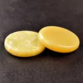 Pair of polished circular yellow jade healing stones on a black leather background - Lemon Jade