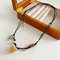 Detalle de collar largo étnico con piña dorada y cuentas de madera sobre cuerda - Collar - Negro - Oro