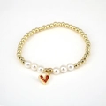 Detail of beaded pearl bracelet featuring gold spheres and a red heart zircon pendant - Red