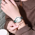 Detail shot of a square quartz watch featuring a colorful woven fabric strap on a wrist - Dark Green