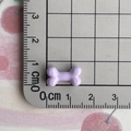 Close-up of a 1.5cm mini purple resin bone charm on a scale mat for size reference - Purple