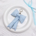 Detailed close-up of blue and white checkered fabric bow keychain with silver lobster clasp - Blue Plaid