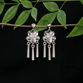 Dettaglio di orecchini a nappa in argento con fiori appesi a un ramo verde - E4963-1 (Nappina a fiore)