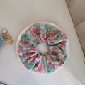 Detailed macro view of a pink floral cotton hair scrunchie on a white ceramic plate - Hair Tie