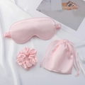 Flat lay of pink faux silk sleep set with an eye mask, scrunchie, and drawstring bag - Light Pink