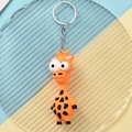Detailansicht eines orangefarbenen Giraffen-Schlüsselanhängers mit großen Augen und Metallring - Giraffe