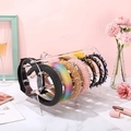 Pink acrylic headband display stand with cylindrical bar on marble surface - Clear