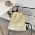 Detail of cream drawstring backpack with embroidered logo on a modern chair - Beige
