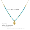 Macro-opname van 18K vergulde Hamsa-hand hanger met blauwe chalcedoon kralen op een stalen ketting - Hand van Fatima & Blauw Witte Kralen (MSNK0172)