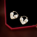 Detail von goldenen Herz-Ohrringen mit weißen Blumen und Zirkonia in einer Schmuckbox - Goldene Blumen Herz Ohrschlaufe