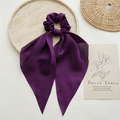 Detail of elegant dark purple satin hair scrunchie with long ribbon on a stylish tray - Purple