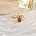 Macro shot of gold ring with teardrop orange gemstone and diamond inlay on white ripple - Orange Pear Gem Luxurious Style (JZ0148A)