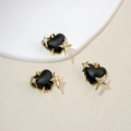 Detail of heart-shaped black resin charms with gold starburst and cubic zirconia inlay - Black