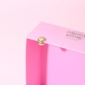 Detail of a pink gift box showing the golden magnetic closure and minimalist typography - Electroplated Gold