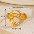 Detailed view of adjustable golden abstract face ring on a warm sandy texture background - Abstract Face Style / Gold Portrait Ring