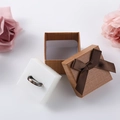 Brown bow jewelry gift box with a black and gold ring set against pink rose petals - 5x5x3.5cm / Brown