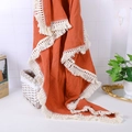 Detail of caramel muslin baby blanket featuring delicate lace tassels and crinkle texture - Orange Red