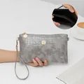 Pochette grigia con motivo a coccodrillo, stemma in cristallo e cinturino da polso. - Grigio