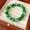 Macro detail of emerald green beaded bracelet with marble texture in a wooden jewelry box - Green