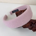 Detail of pink wool felt headband showing thick texture and handmade label on wooden stand - Pink