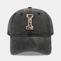 Close-up of vintage black baseball cap featuring leopard print letter I patch embroidery - Letter I
