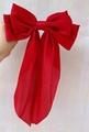 Large red satin bow hair clip held in hand featuring elegant silk ribbon finish - Red