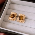 Close-up of vintage gold hollow earrings with oval tiger eye stone in a gray velvet box - Gold Style / Silver Earring Post-Gold-Coffee
