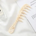 Gedetailleerde macro-opname van beige marmeren acetaat kam op zachte witte stof achtergrond - Beige Marmer