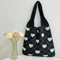 Knitted heart pattern tote bag in black and white displayed with elegant roses - Black and Apricot