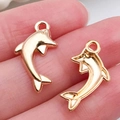 Gold plated dolphin charms for DIY jewelry making shown on finger for scale - Dolphin Pendant 11x20mm