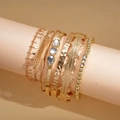 Dettaglio di un set di 6 bracciali dorati con strass scintillanti e texture martellate - Oro (Set da 7 pezzi)
