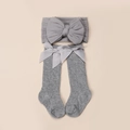 Detail von grau gestricktem Baby-Stirnband und Socken-Set mit großen Hohlbogen-Dekoren - Wadenhoch / Grau
