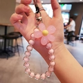 Pink macaron beaded phone strap with flower charm held by hand for wrist styling - Pink Flower Pink Beads