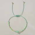 Detalle de pulsera tejida a mano con cuentas de semillas y piedra central verde claro - Aventurina Verde Pálido Trenzada