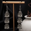 Detailed shot of silver triple-tier Jhumka earrings with ornate floral carving - H4184 Antique Silver