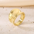 Wide golden stainless steel infinity ring on a beige stone surface with silk fabric - US 6 / 14mm Gold Smooth Style