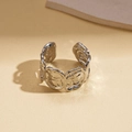 Close-up of silver geometric open ring with abstract lava texture on a textured surface - Rose Relief Style / Silver