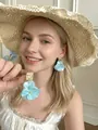 Close-up of blue petal-shaped handmade resin earrings on a model with a straw hat - 18# 925 Sterling Silver Earring Post-Blue-Large Resin Petals (HE24970)