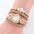 Détails macro d'une montre à quartz dorée avec lunette en strass et bracelet perles - Style Beige (1)